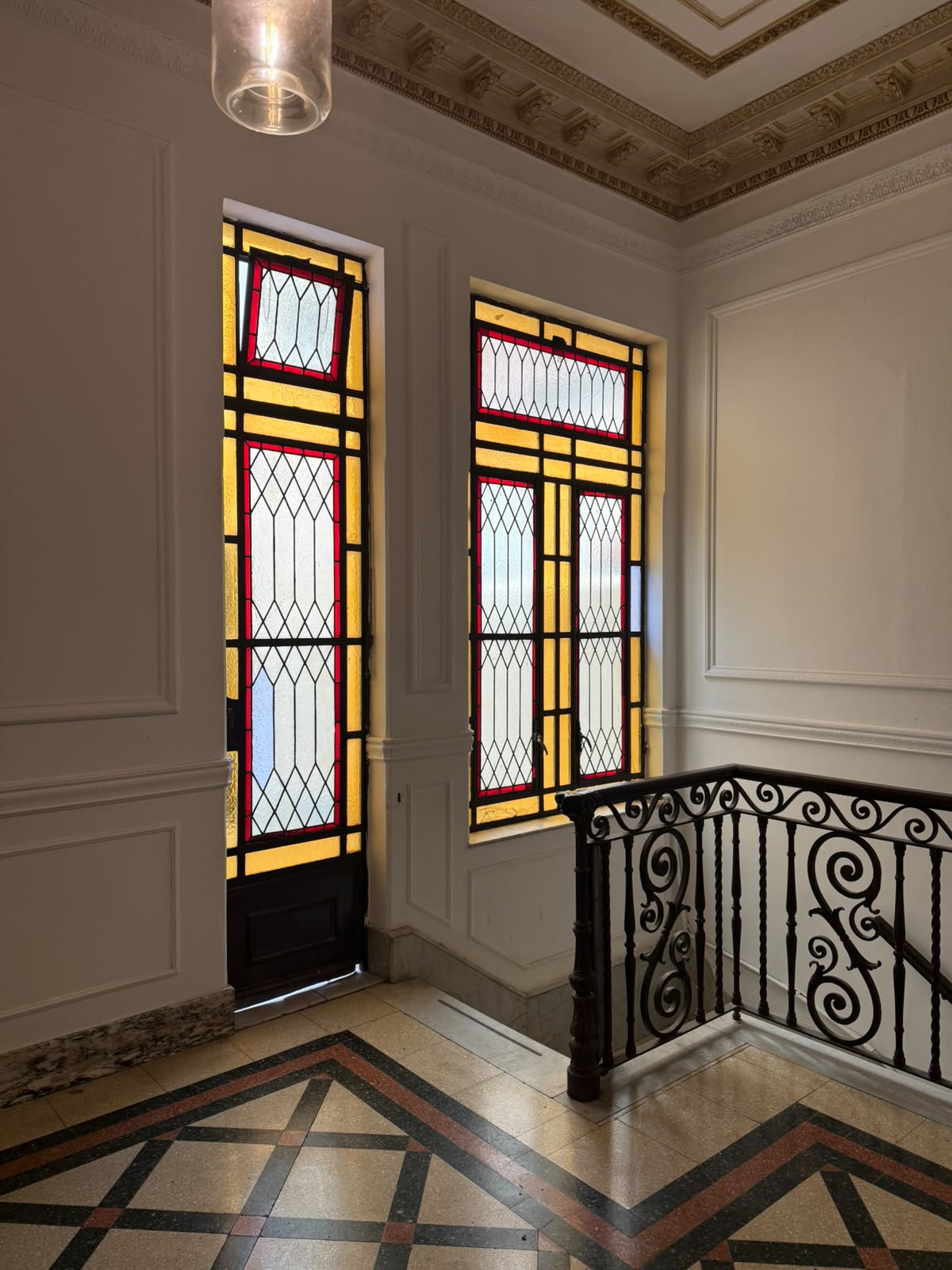 Escalera histórica, vitrales y pisos geométricos de la sede